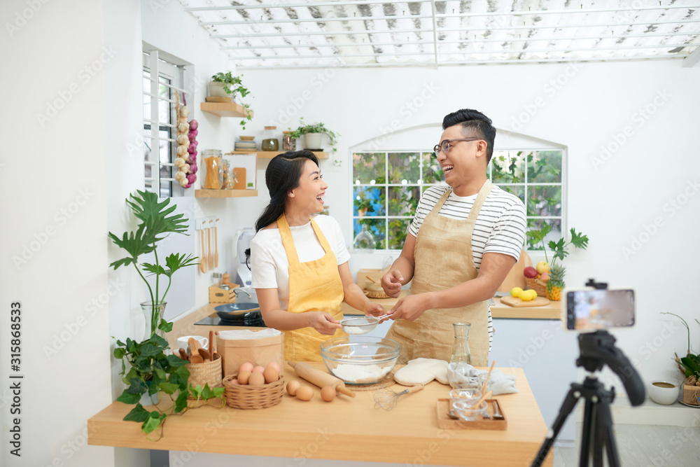 年轻的亚洲夫妇一起做饭，并为vlog和社交媒体录制视频