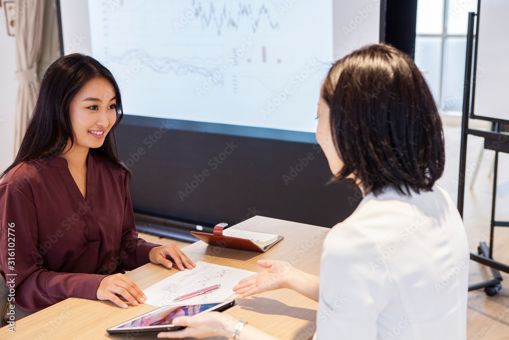 女性社員たちがタブレットを見ながら打ち合わせをしている