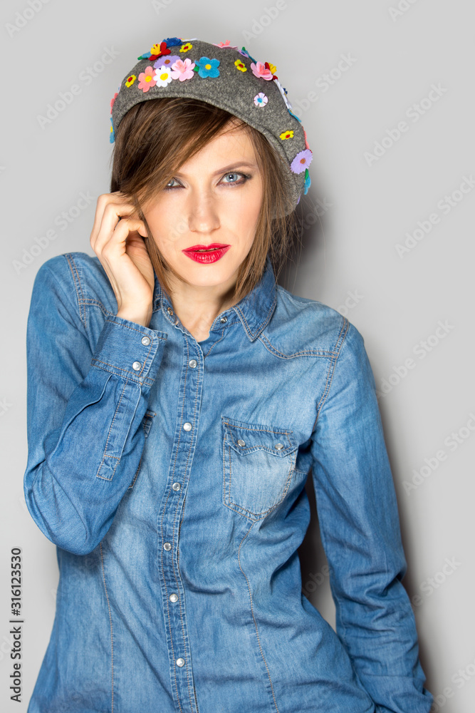 young beautiful happy stylish hipster girl wearing denim shirt and funny cap with flowers