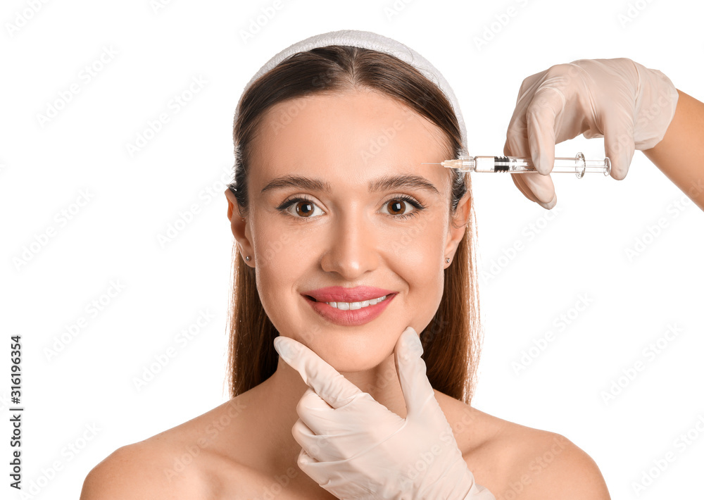 Young woman receiving filler injection against white background