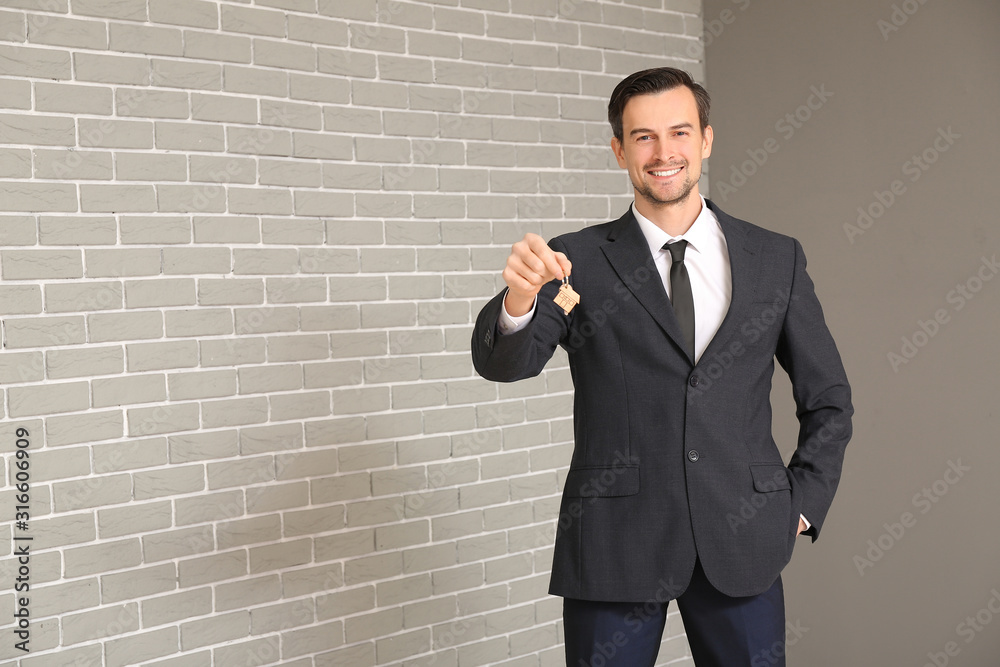 Portrait of male real estate agent with key indoors