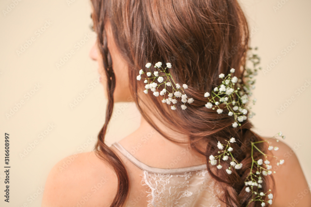 Beautiful young woman with long hair and flowers on color background