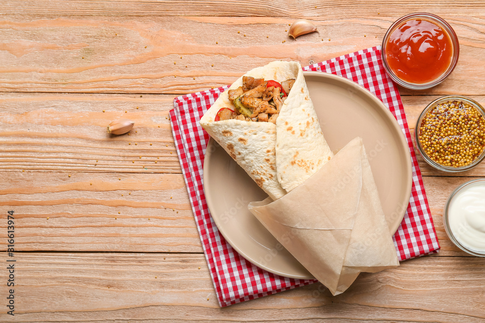 Tasty doner kebab and sauces on wooden background