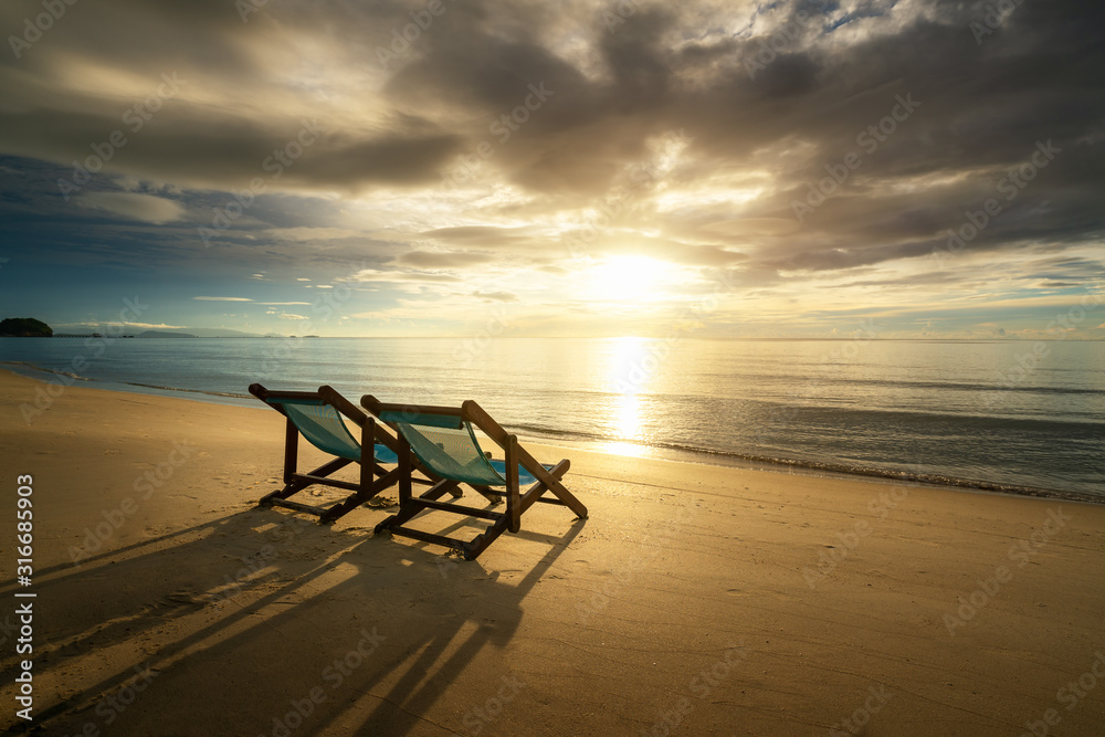 Two Beach Chairs standing in beach with beautiful sea and sunlight in background at island in Phuket