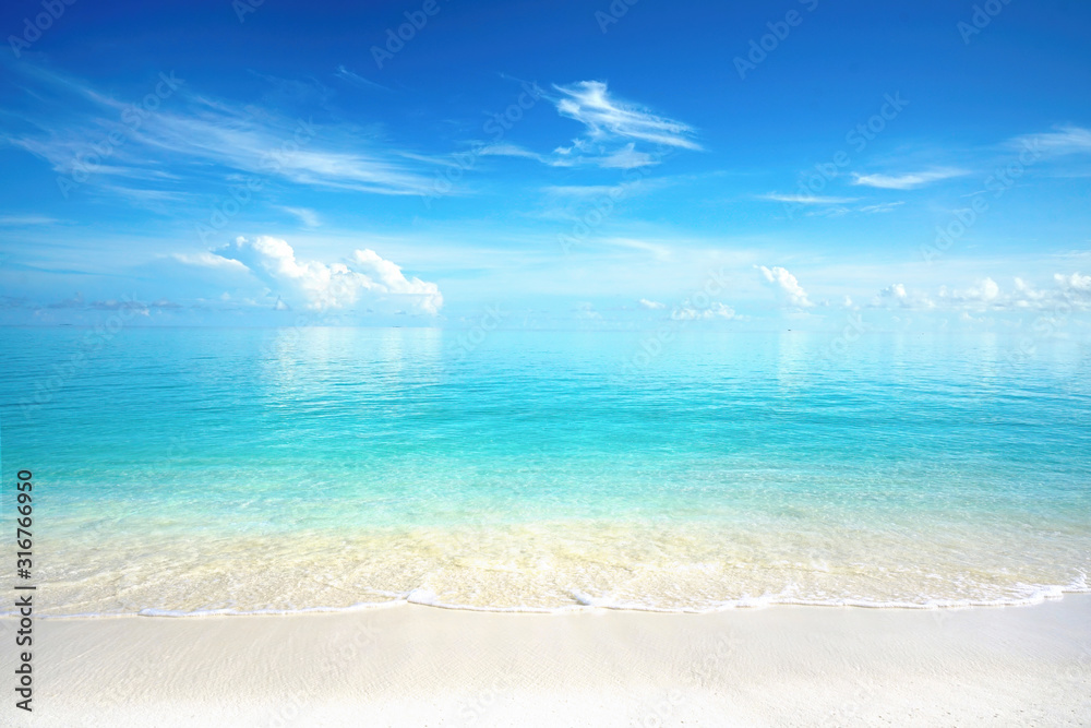 Beautiful sandy beach with white sand and rolling calm wave of turquoise ocean on Sunny day. White c