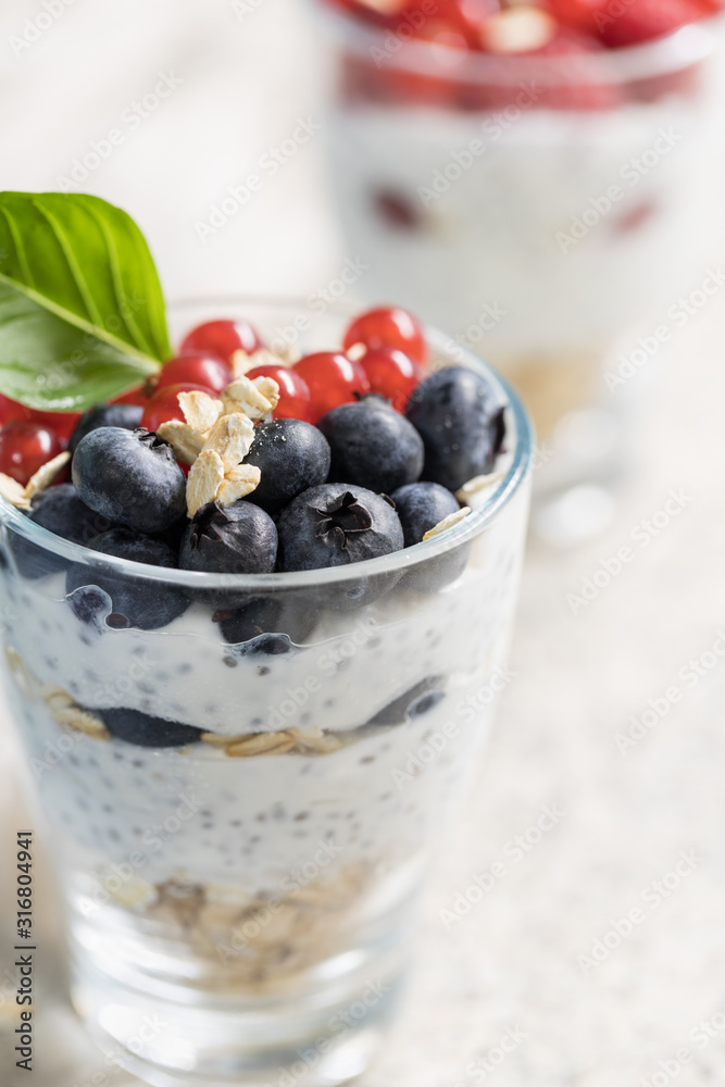 Delicious yogurt pudding with chia seeds, oats, berries and fruit in glass jars for healthy eating  