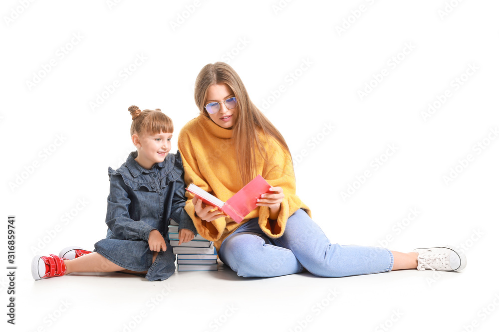 Beautiful young woman and her little daughter reading books on white background