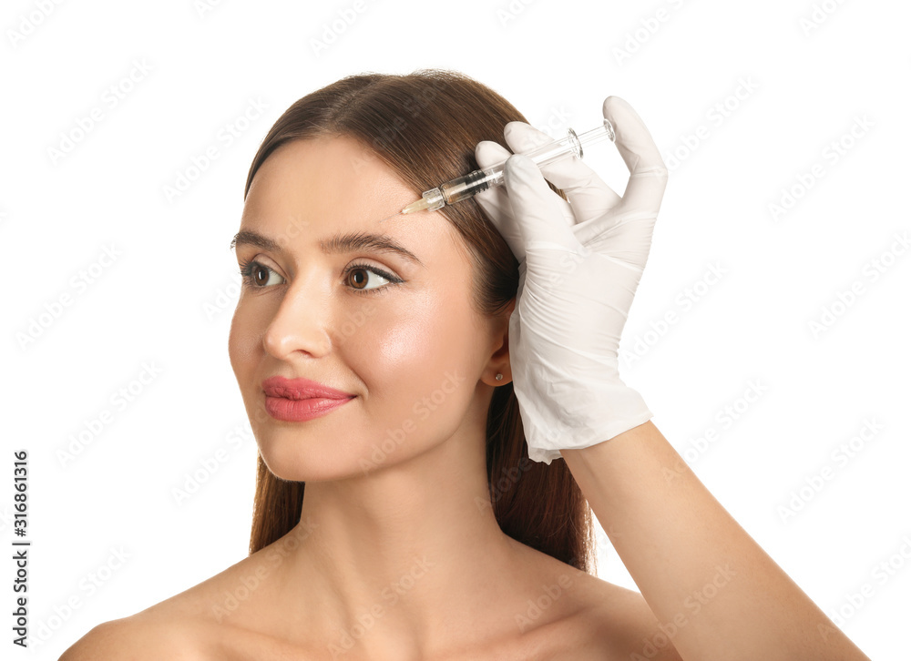 Young woman receiving filler injection against white background