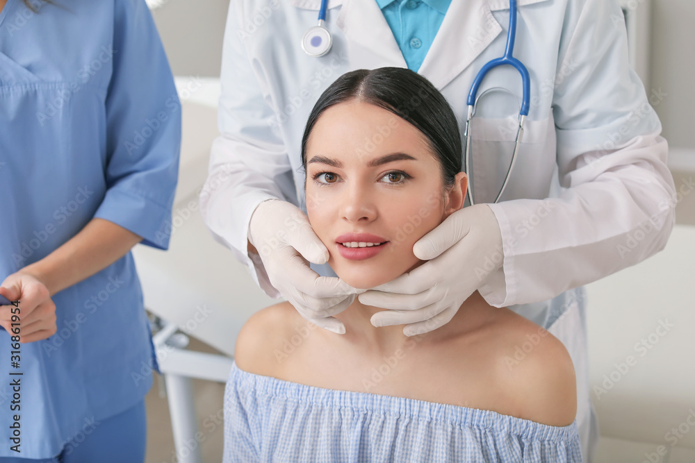 Plastic surgeon examining young womans face prior to operation in clinic