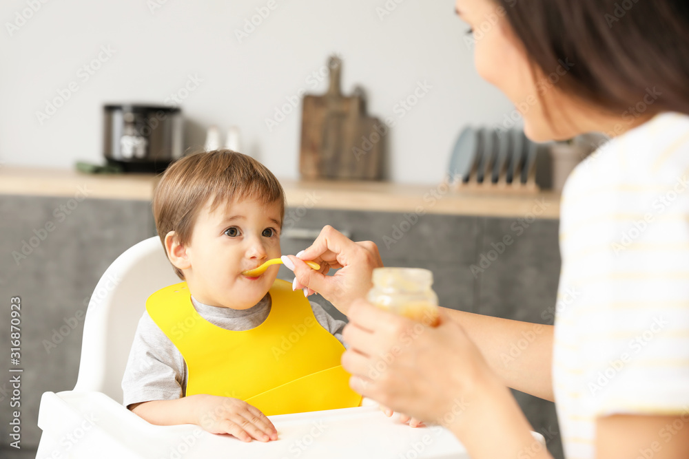 Mother feeding her little son in kitchen