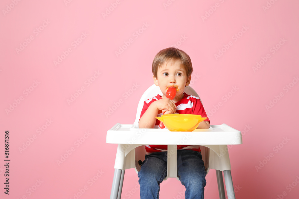 可爱的小男孩在彩色背景下吃美味的婴儿食品