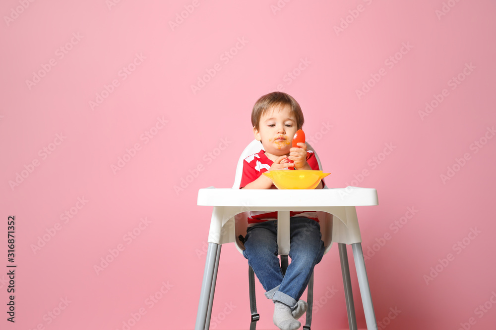 可爱的小男孩在彩色背景下吃美味的婴儿食品