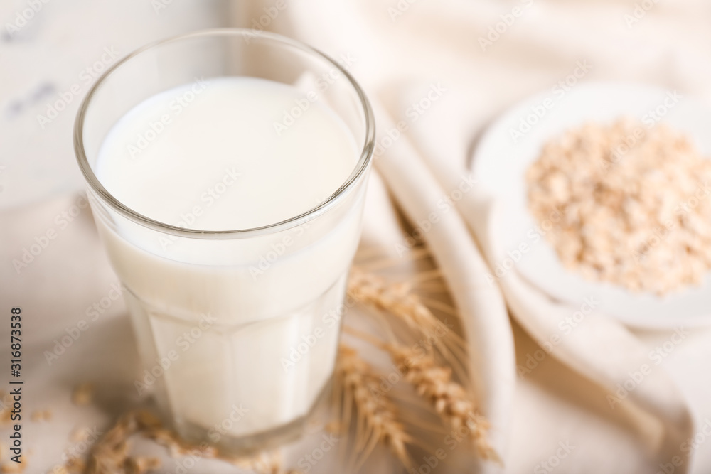 Glass of tasty oat milk on table