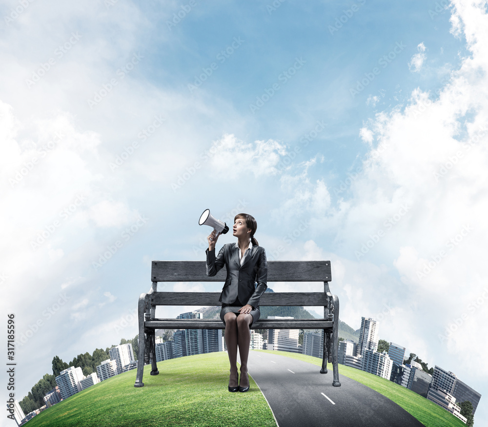 Business woman with megaphone on wooden bench