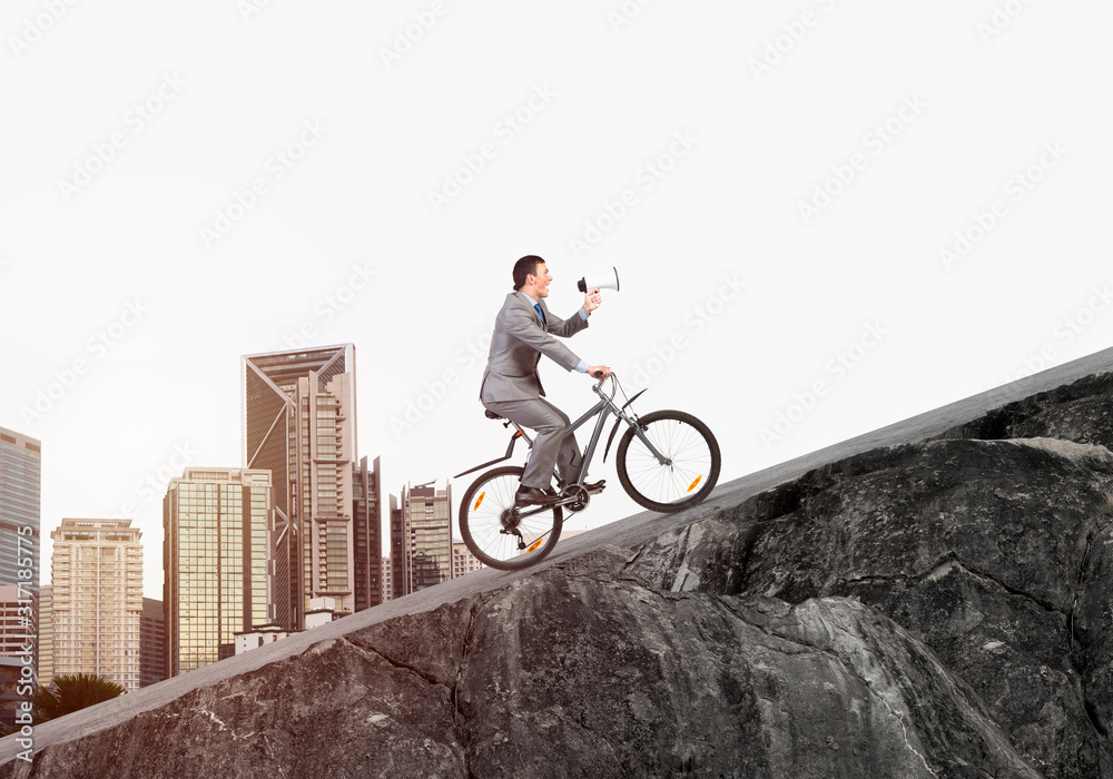 Businessman with megaphone in hand on bike