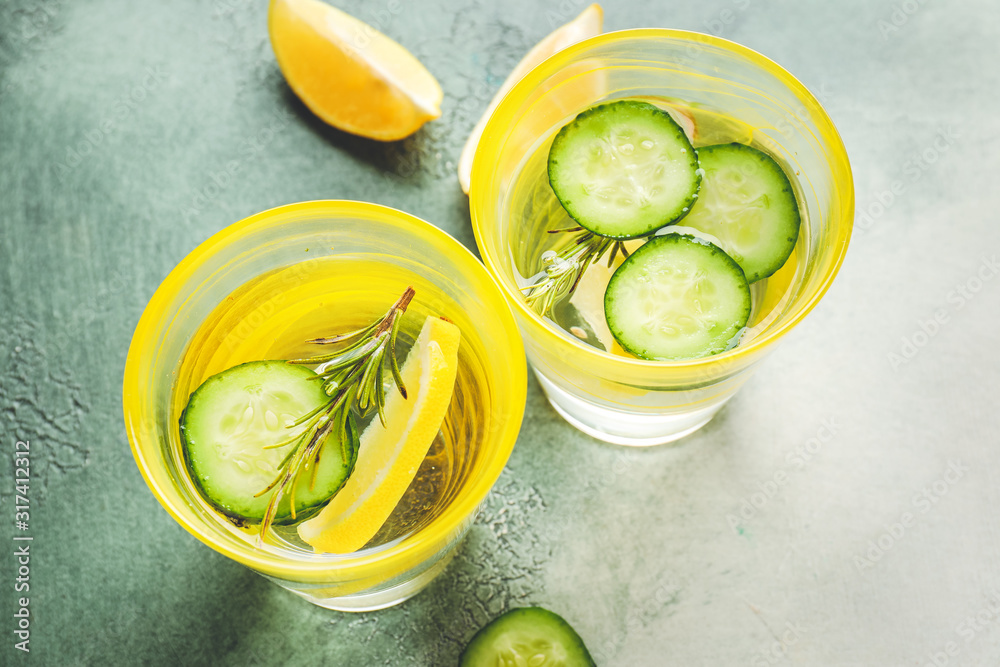 Glasses of cold cucumber water on color background