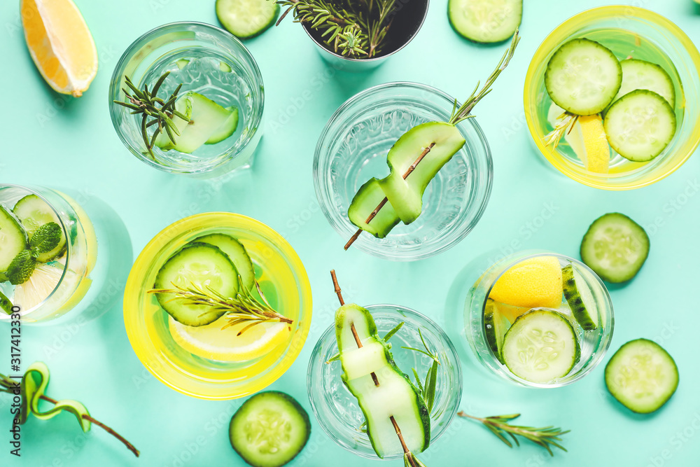 Glasses of cold cucumber water on color background