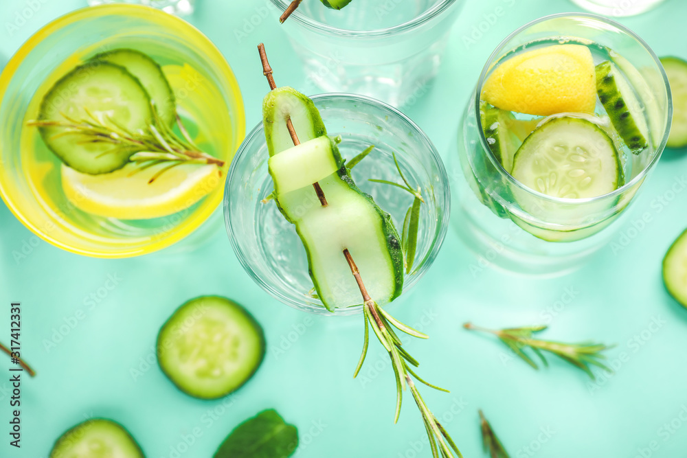 Glasses of cold cucumber water on color background