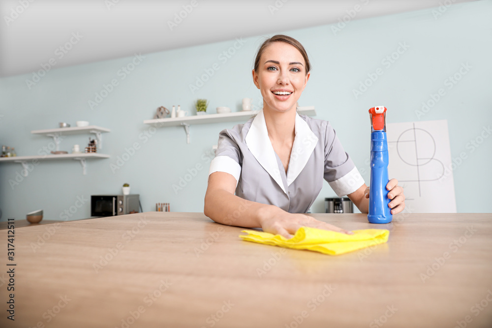 Beautiful young chambermaid cleaning kitchen