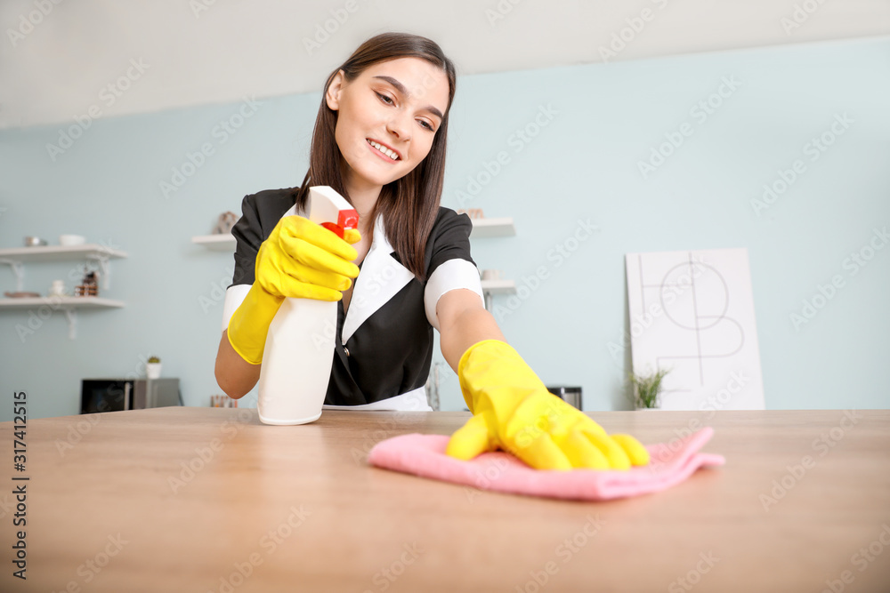 Beautiful young chambermaid cleaning kitchen