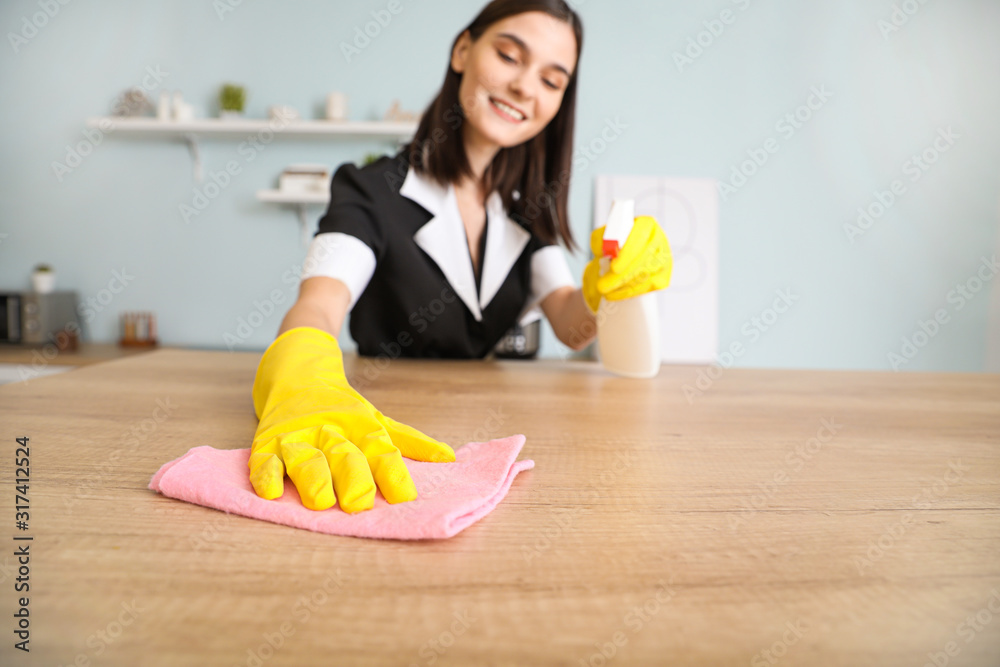 Beautiful young chambermaid cleaning kitchen