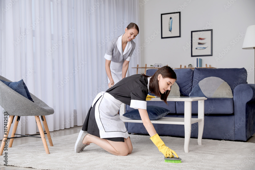 Beautiful young chambermaids cleaning hotel room