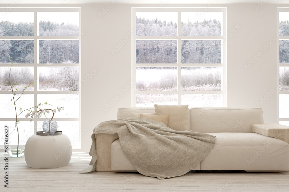 Stylish room in white color with sofa and winter landscape in window. Scandinavian interior design. 