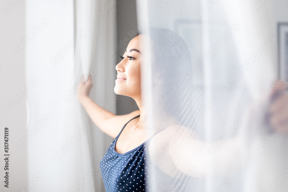 亚洲女孩穿着睡衣早上在家打开窗户的蕾丝窗帘