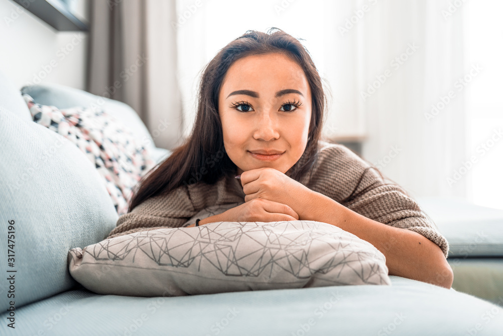 Relaxed asian girl lying on sofa at home in calm leisure time