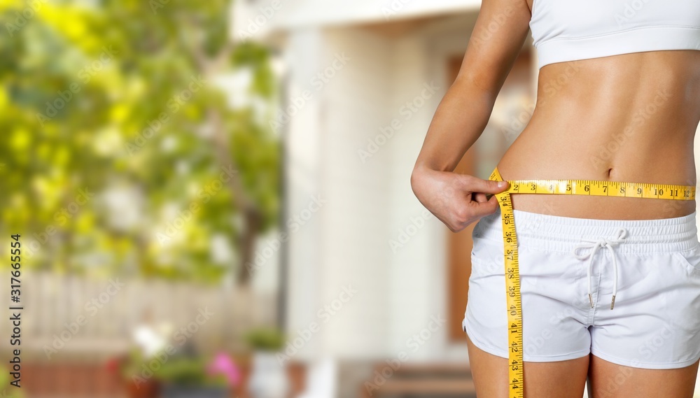 Slim young woman measuring her thin waist