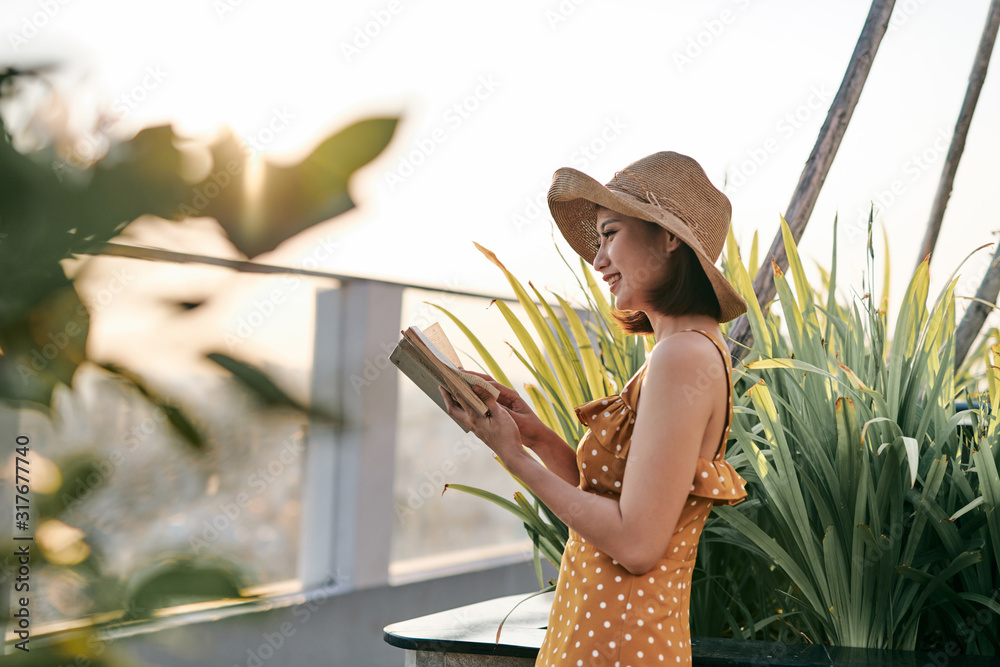 Young Asian girl reading in nature under summer sunshine