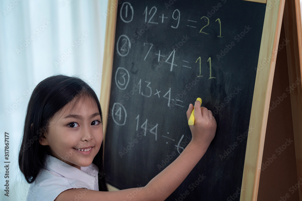 Asian girl write and do home work on the backboard before back to schoo