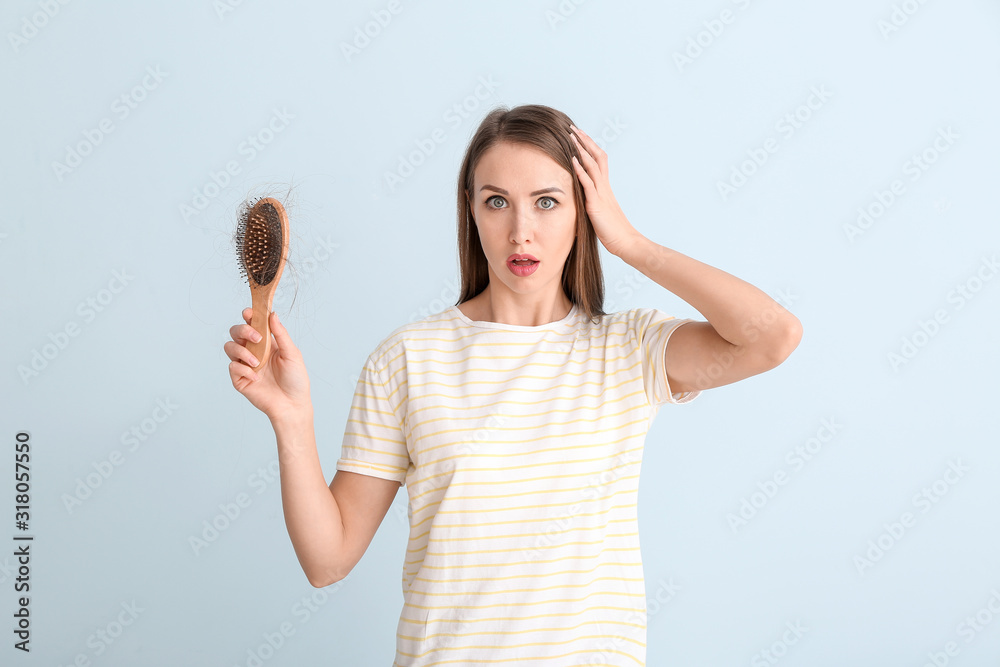 Young woman with hair loss problem on color background