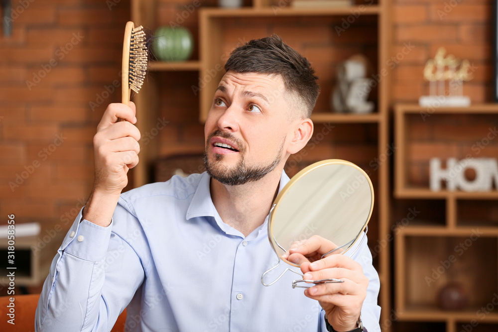 Worried man with hair loss problem at home