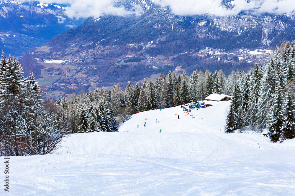 Ski piste in fir and pine forest covered with snow after strong snowfall over Mont-Blanc mountain ra