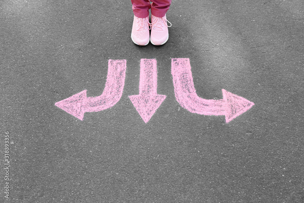 Person standing on road with arrows pointing in different directions. Concept of choice