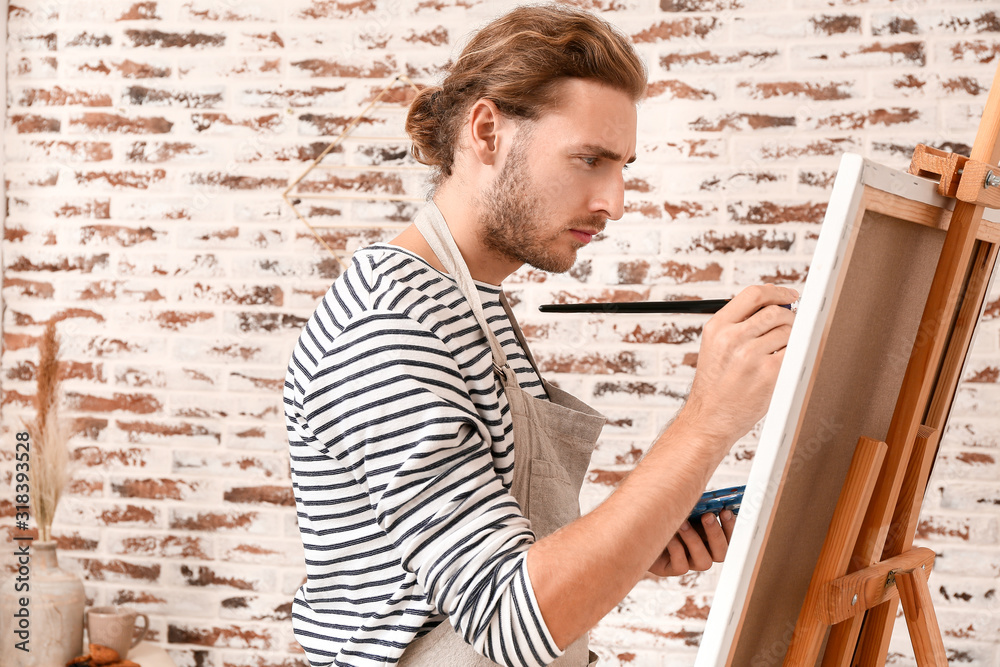 Young male artist painting at home