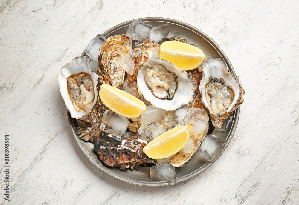 Plate with tasty cold oysters on white background