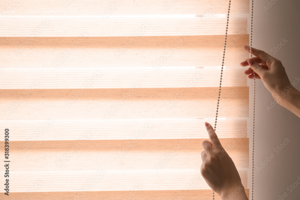 Woman opening blinds on window