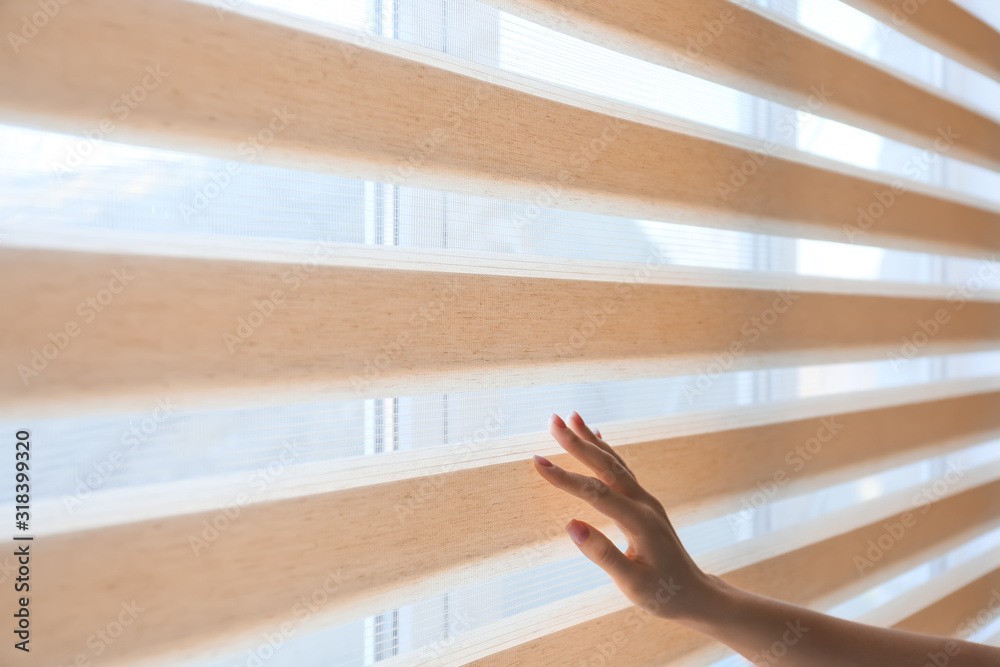 Woman opening blinds on window