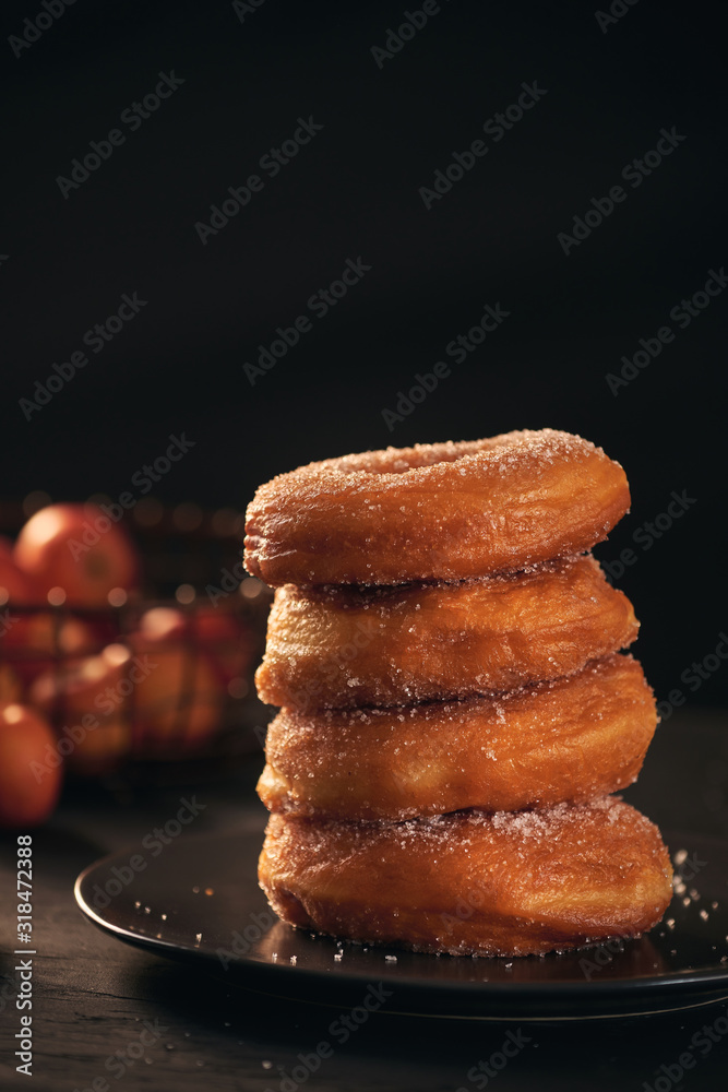 On a dark wooden surface with a black background donuts are stacked