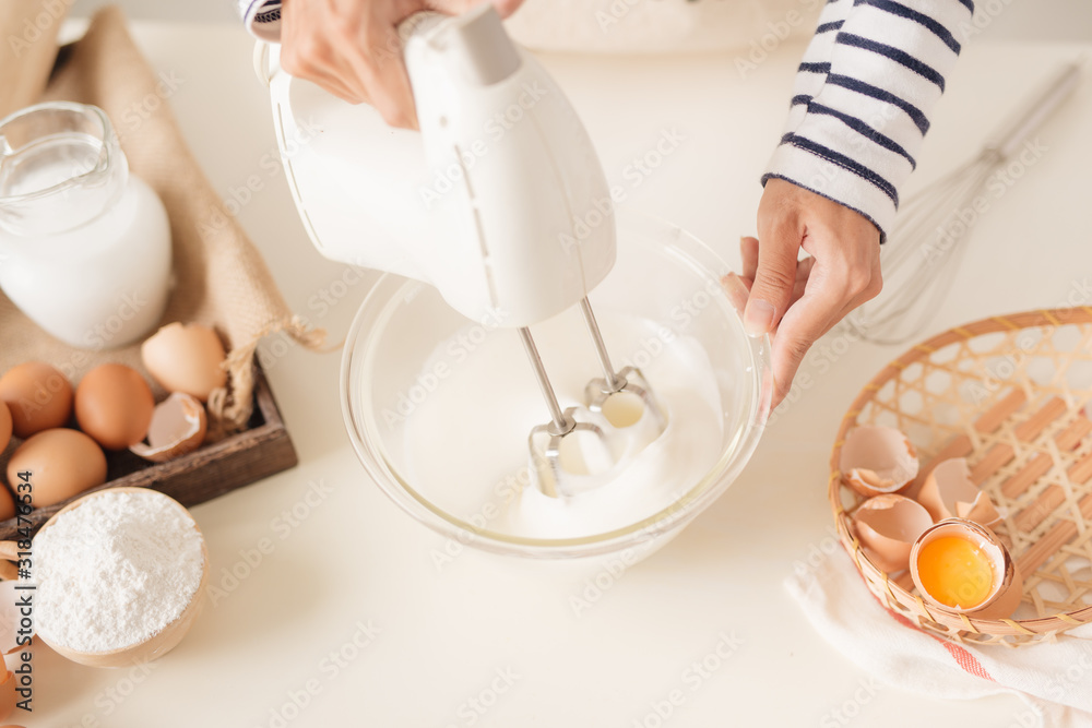 Mixing white egg cream in bowl with motor mixer, baking cake