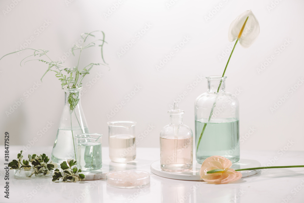 Perfume oils concept. Laboratory glassware with infused floral water on table