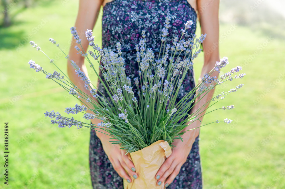  Beautiful woman with lavender flowers in hand over green natural background