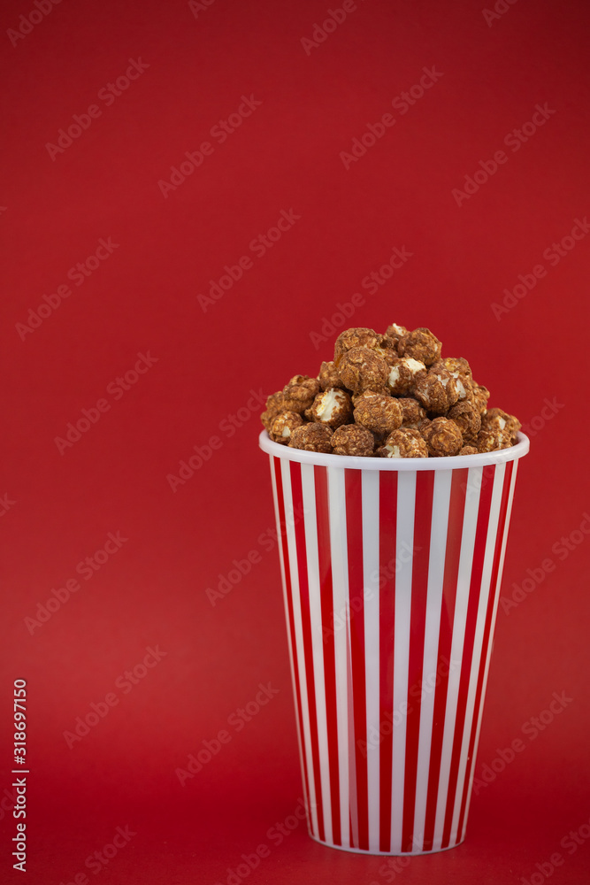 Butter popcorn in a red popcorn cup, snack in the house or cinema on a red background