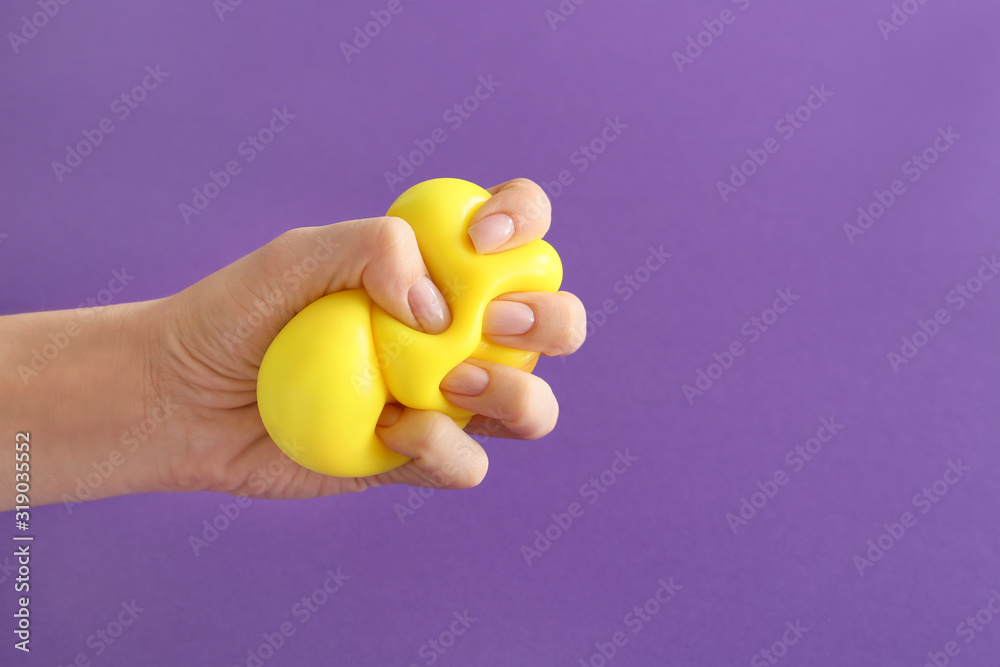 Hand squeezing stress ball on color background