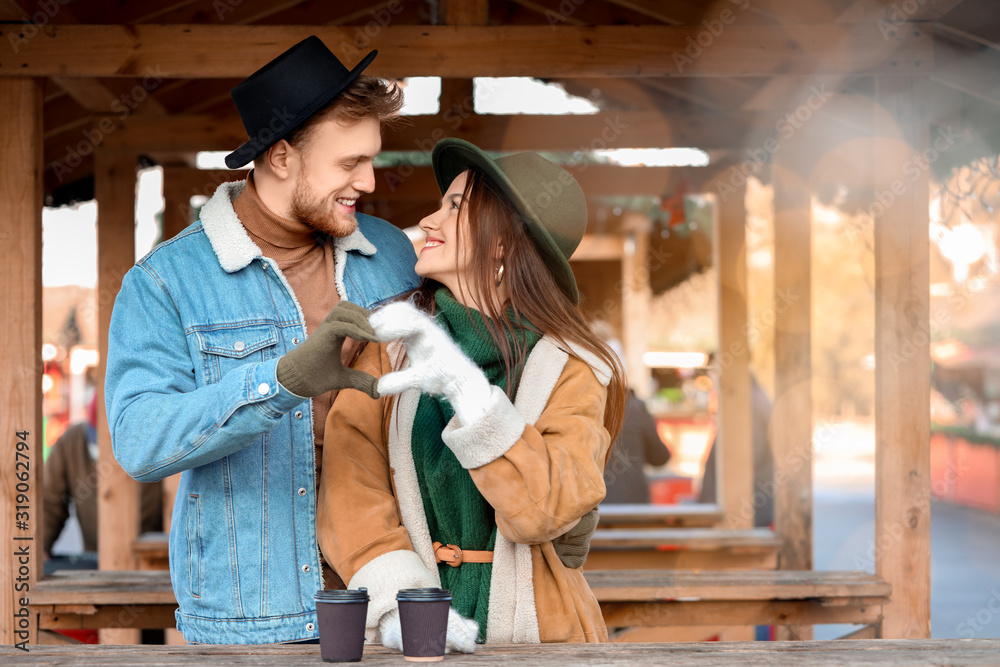 Happy young couple making heart shape with their hands outdoors on winter day