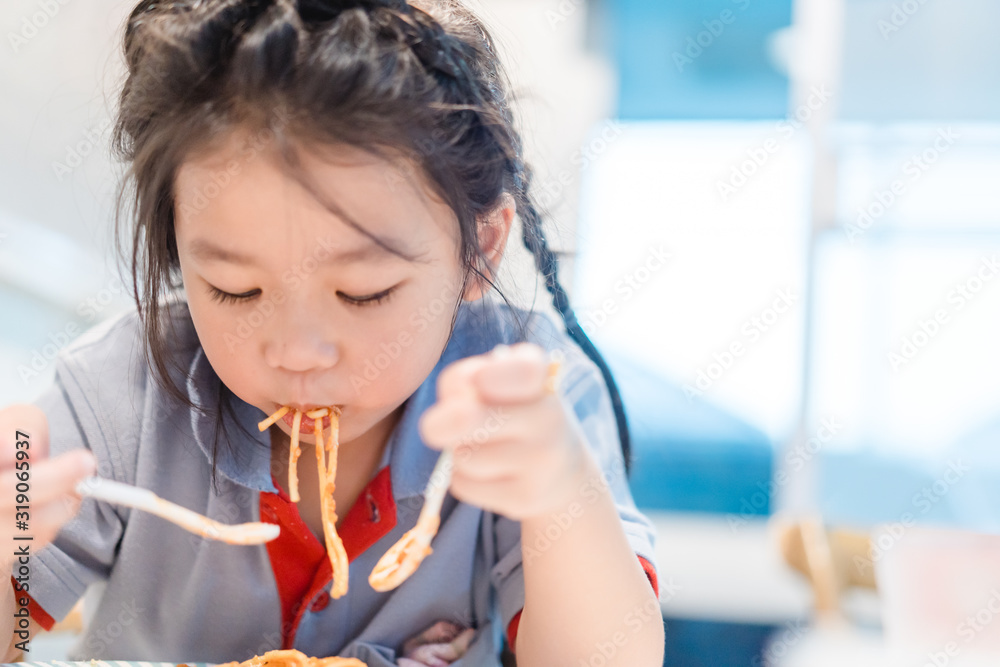 Hungry face and enjoy eating concept.Little asian girl enjoy eating with spaghetti bolognese with ch