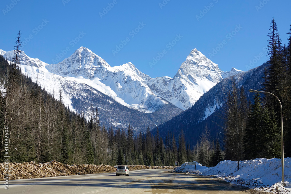 脏兮兮的白色SUV沿着雪山下风景优美的高速公路行驶