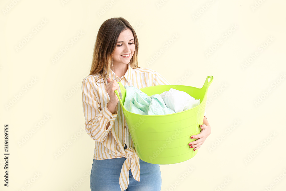 Beautiful young woman with laundry on color background